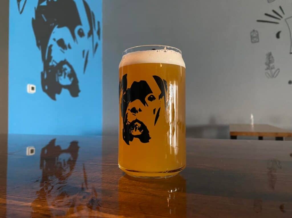 image of a beer on a table, with the image of a boxer dog. A painting of a boxer dog is behind it. The scene is at Wicked Boxer Brewery, a dog friendly brewery in Cypress TX